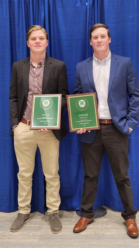 Two young men in formal clothing holding 4-H plaques.
